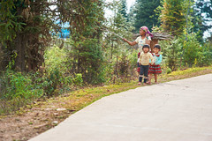 A mother and her children walk along the road- Yunnan, China