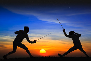 Silhouette fencers with sunset