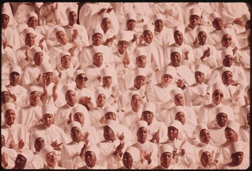 15-0673MBlack Muslim Women Dressed In White Applaud Elijah Muhammad During The Delivery Of His Annual Savior's Day Message In Chicago, 03/1974