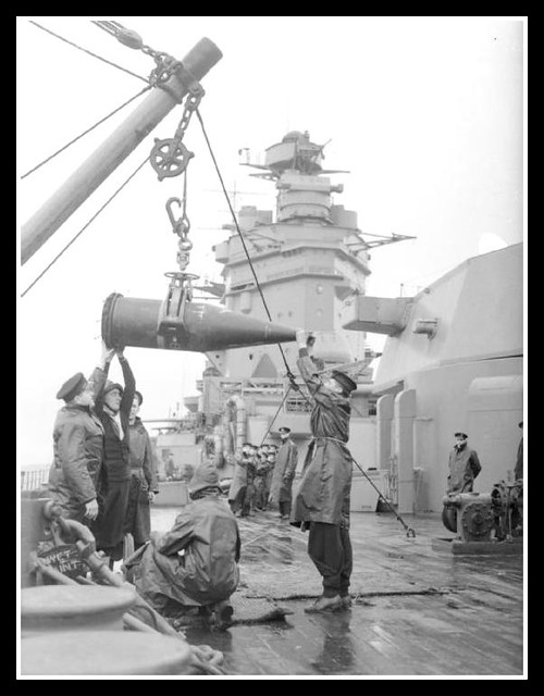Enormous   16 inch shells being lowered on to HMS RODNEY's deck from the ammunition ship. Each one weighs a ton and will fire over ten miles.   HMS Rodney fired 340 16