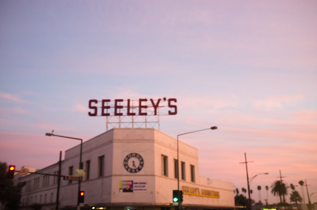 Seeley's Furniture building with rooftop neon sign silhouetted against a pink dusk sky.