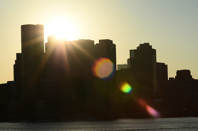 Sunset over downtown Boston, from across Boston Harbor in Piers Point Park, East Boston, with lens flare