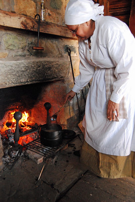 A costumer interpreter shared enslaved history while tending to soup on the hearth.