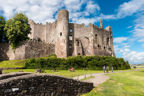 impressive laugharne castle carmarthenshire wales fort fortress fortification battlement wall tower architecture ruins bridge tree bush grass path outdoor landscape people