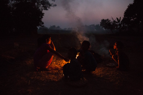 Sangharsa - stories of women's struggles by D J Clark, Children sit round a fire at sunset. Kalpana is a former ‘Kamaiya’ (bonded labourer). Now, she runs