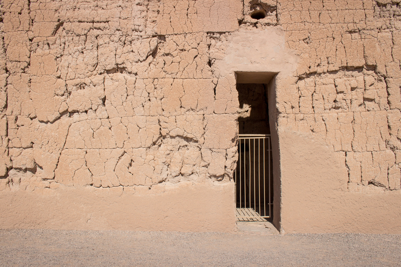 The sun illuminates a tall doorway in an earthen wall