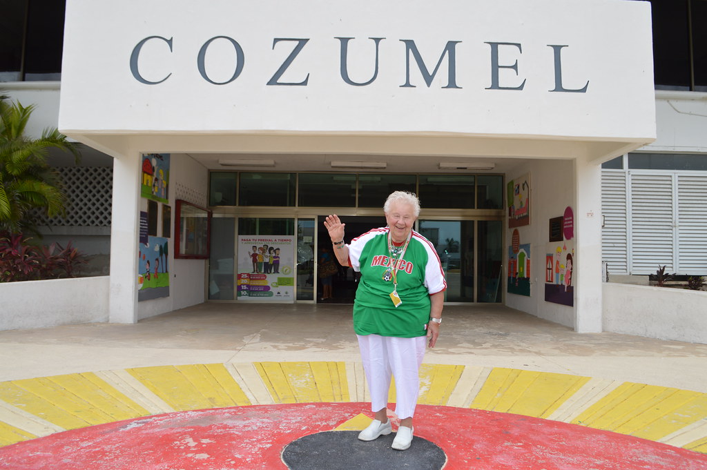 Theresa Irene Wolowski waving hola from the Palacio Municipal Cozumel building in Cozumel, Quintana Roo, México