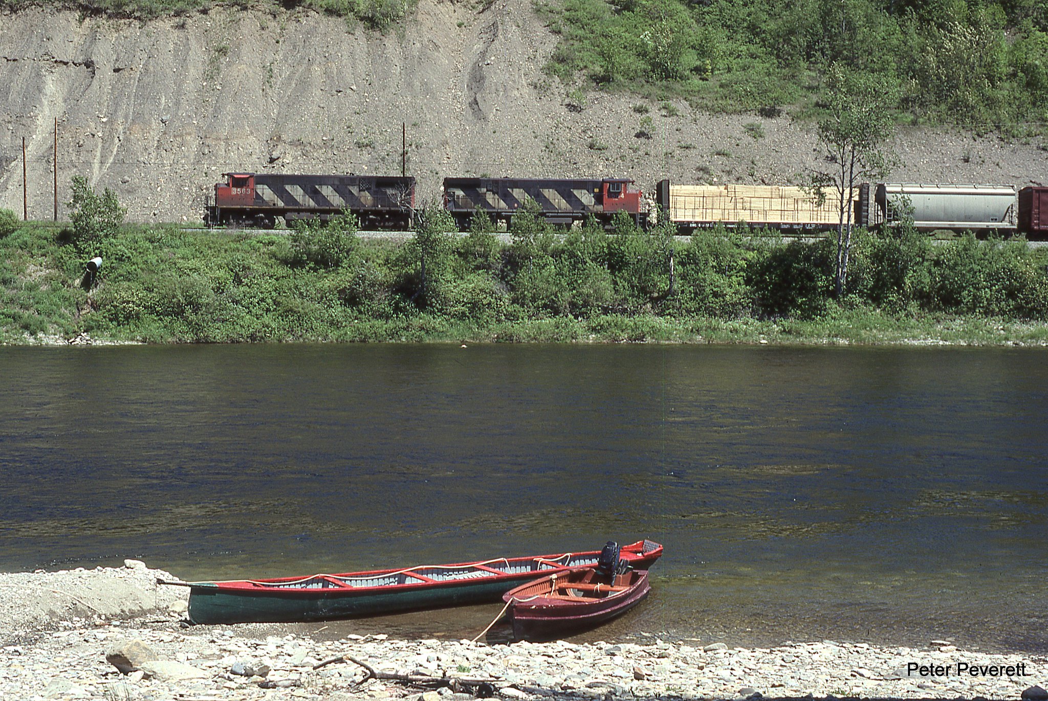 By my math 99 % of people visiting the Matapedia River Valley are there for world famous salmon fishing.  For the other 1 % there is some other reason. Not too long after CN sold its lines between Mont Joli - Moncton and Matapedia - Gaspe we see Chaleur Bay Railway w/ CN M-420 # 3563, 3554 at Clark Brook, Quebec June 9, 1998.  Here they will meet a Matapedia Railway train out of Mont Joli and swap cars.  The train is passing a long square stern canoe common to the area for the other 99%s'. 