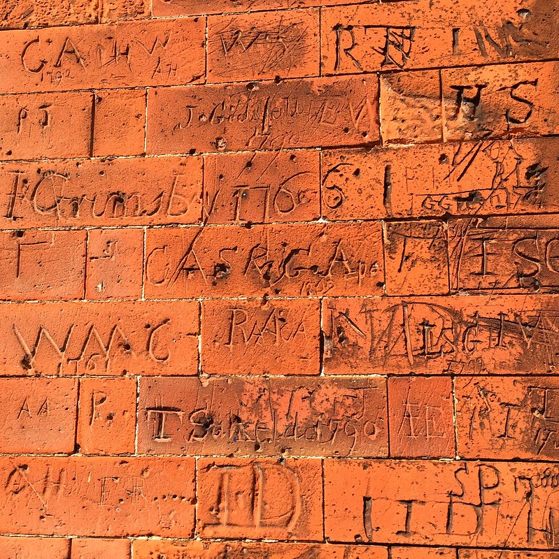 terra cotta brick wall with initials etched into it