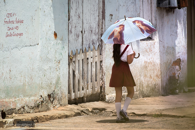 Carrying naked-lady umbrella for sun protection, Vinales, Cuba