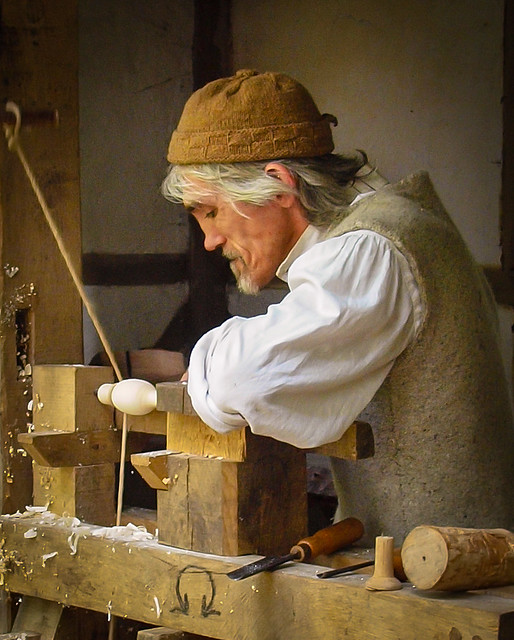 Tom the wood turner uses a pole lathe to fashion a wooden spoon at Little Woodham Living History Village