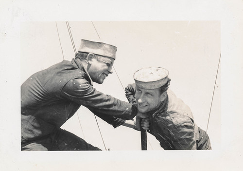 Two sailors tigtening something off camera