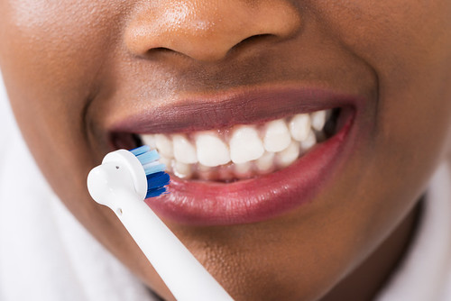 Close-up Of A Woman Brushing Teeth With Electric Toothbrush | by rtcmedia
