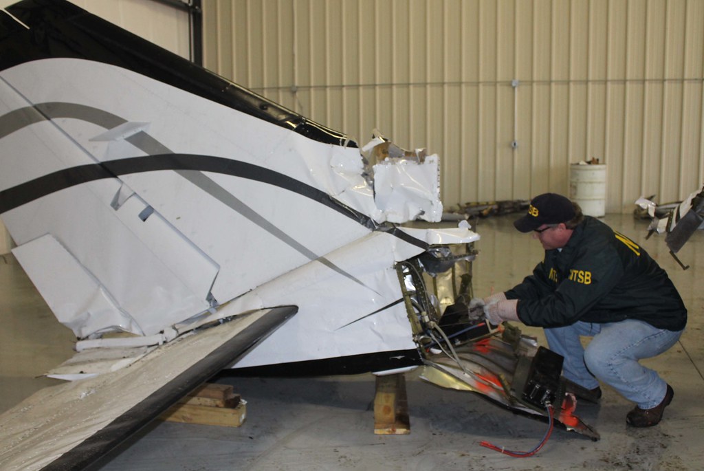 NTSB air safety investigator Todd Fox examines the tail section of the Cessna 414A