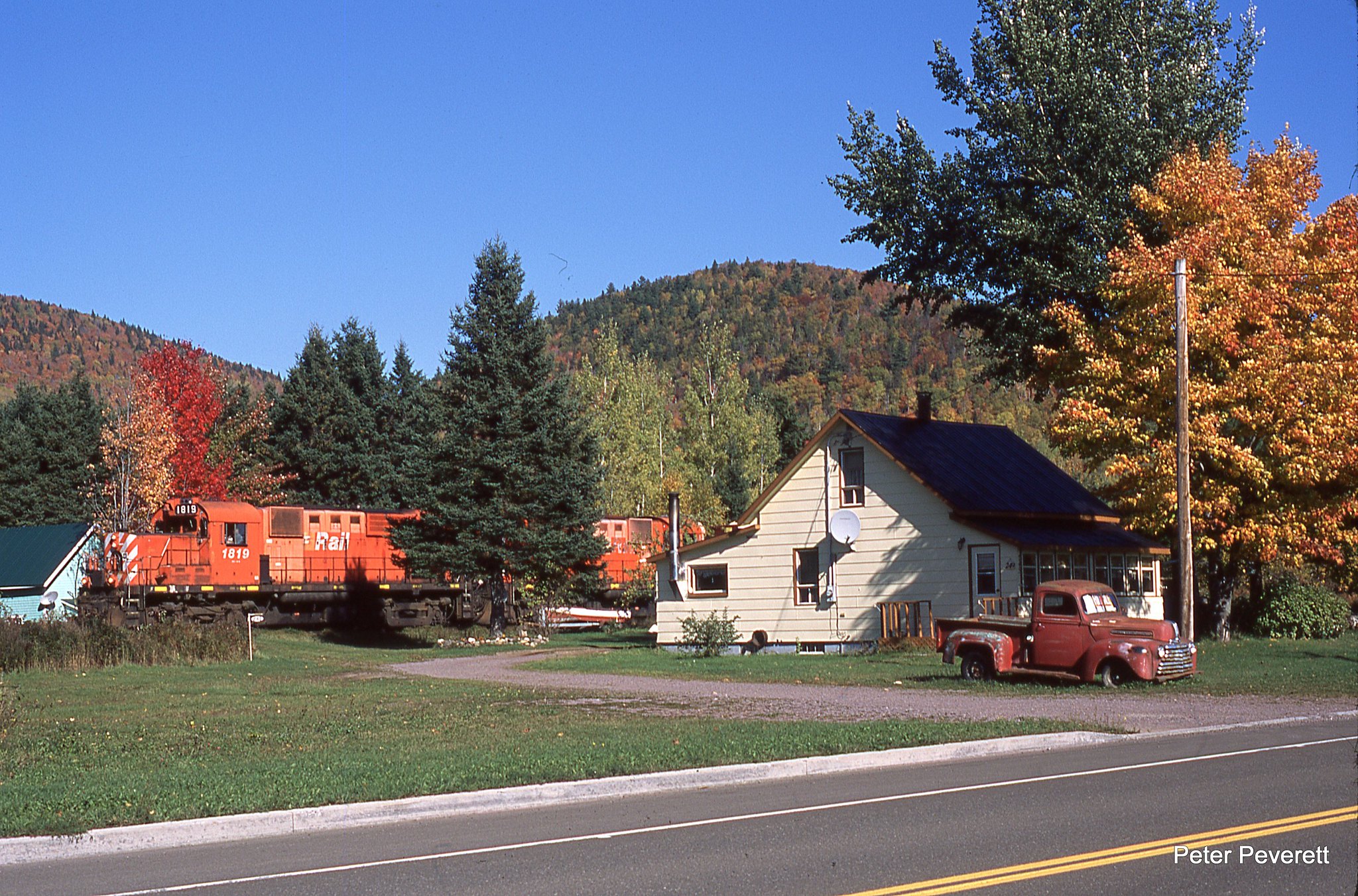 Chaleur Bay RS-18 # 1819, 1849 are westbound passing a old truck for sale in front of a house in Pointe-a-la-Croix, Quebec Oct. 5, 2010