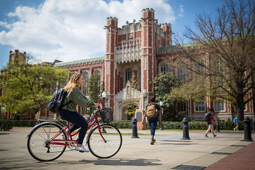 students one on bike in front of bizzell library