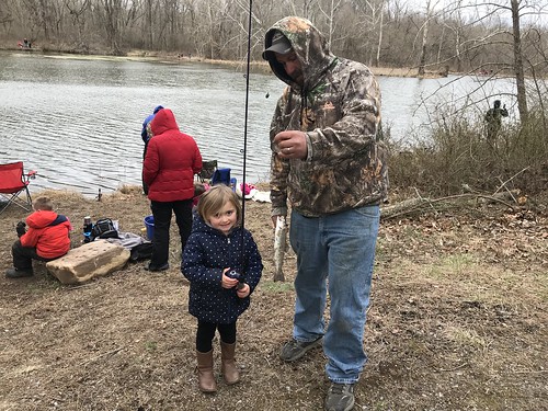 Photo of young girl with her father showing off a fish she caught