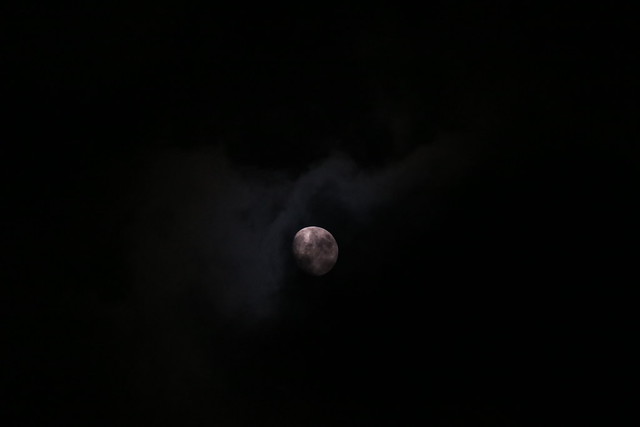 The moon glimmers through the clouds.
