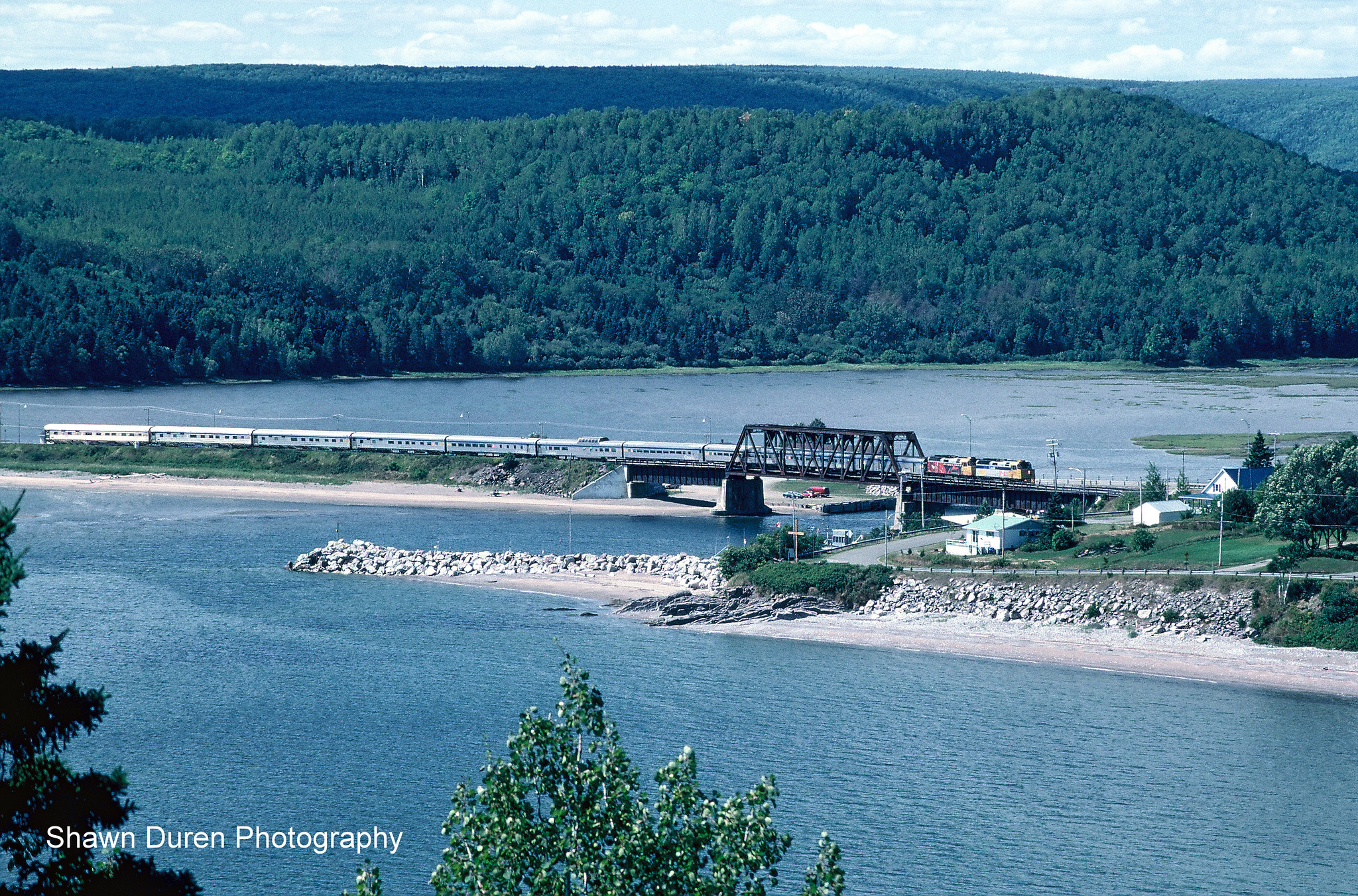On top of Le tunnel du Cap-à-l'Enfer, is a scenic lookout over Port Daniel, Quebec. Here, VIA Rail Train #16, the Chaleur crosses a bridge before coming through the tunnel underneath. August 15, 2005. 