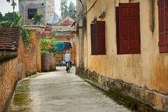 Elderly man riding a bicycle down an alley way