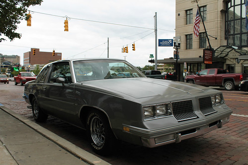 flint michigan genesee county urban city summer august 2017 home town annual backtothebricks car festival show week downtown saginawst firstst intersection mottfoundation building 1983 oldsmobile olds cutlass supreme 2door coupe generalmotors gm gbody rwd midsize intermediate platform personal luxury gray grey front threequarter view curb street parallel parked parking clouds cloudy american flag raised white letter tires