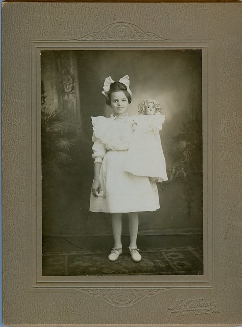 A lovely child with bow holds her doll odd  size cardboard