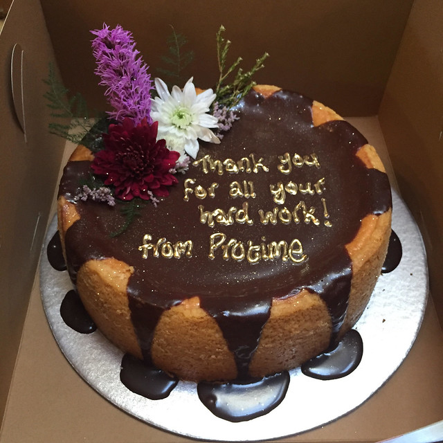 Double Chocolate Cheesecake with piped gold message and fresh flower arrangement