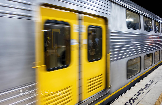 A suburban train rushing by the platform of an underground station