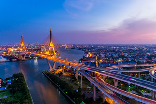 Aerial view of Bhumibol suspension bridge in Bangkok city with light trails of car on the road at sunset sky and clouds in Bangkok Thailand.